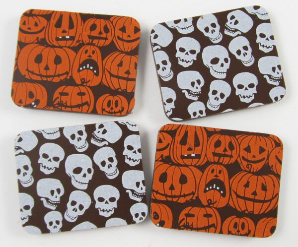 Four coasters with skulls and pumpkins on them.