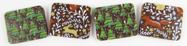 Four brown and green coasters with deer and trees on them.