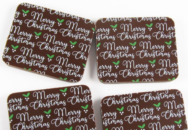 Four chocolate coasters with merry christmas written on them.