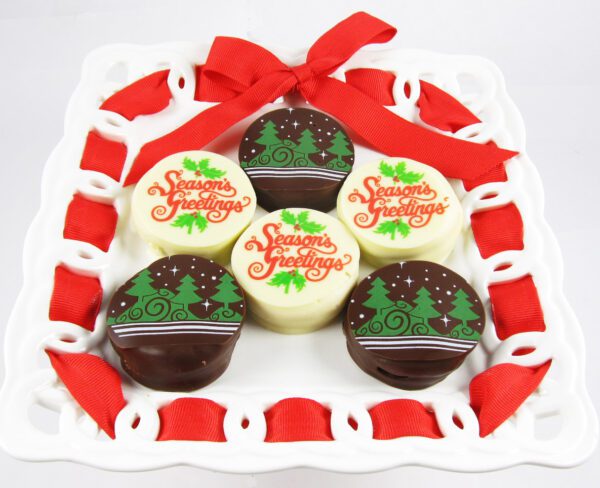 Four chocolate cookies on a white plate with a red ribbon.