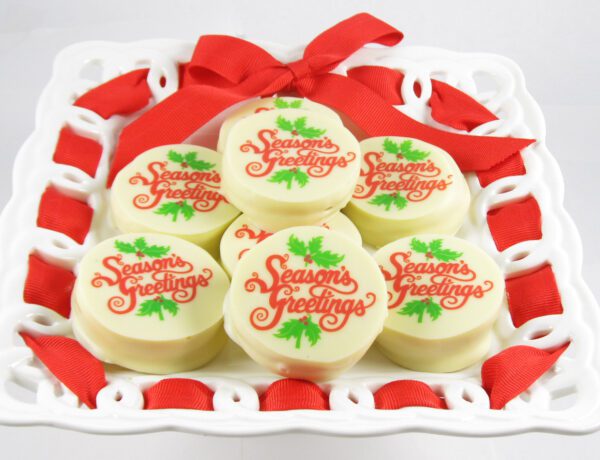A tray of white chocolates with red ribbons on it.