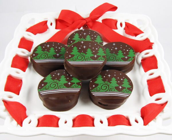 Five chocolate covered christmas trees on a white plate.